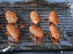 烤盘铺上锡纸，将鸡翅放在烤架上。刷上一层蜂蜜