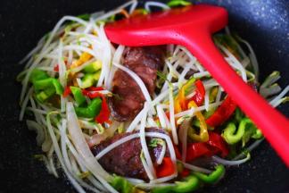 看见绿豆芽炒至变软时，加入青红椒