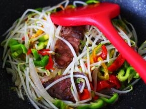 看见绿豆芽炒至变软时，加入青红椒