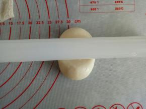 取一个包好的面团，用擀面杖在中间压一下