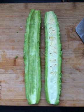 将苦瓜洗净，去头去尾，对半切开，去掉中间的芯。