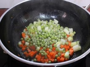 接着炒蔬菜粒了，锅中加少许油，把胡萝卜粒、甜豆、西芹粒倒入锅中，中火翻炒至九成熟。