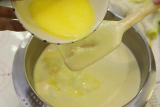 牛奶、柠檬汁和黄油混合物隔水加热至40度，利用刮刀阻隔奶油混合物，倒入蛋液糊内。
