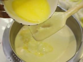 牛奶、柠檬汁和黄油混合物隔水加热至40度，利用刮刀阻隔奶油混合物，倒入蛋液糊内。