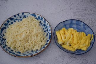 锅中烧开水，放入面条煮熟捞出加入少许食用油拌匀备用，锅中倒入适量的食用油烧热，把鸡蛋液煎成蛋饼取出切丝备用