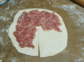 拿一面团擀压成薄片，中间切一刀，如图将肉末平铺在饼皮上，四周要留空白处