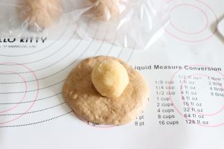 取一个压扁，稍微擀开一下，放入椰蓉球。