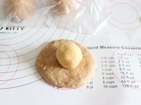 取一个压扁，稍微擀开一下，放入椰蓉球。