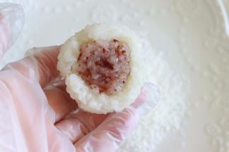 继续放入蒸锅，蒸大约10分钟，尝一下是否完全熟透后，就拿出来晾到温。取一部分蔓越莓糯米，包入一部分蔓越莓果泥，再用白色糯米，包住他们。这步一定要带好防粘手套哦，如果没有的，需要准备一些白开水晾凉，沾一点水来操作。但是不可以沾太多的水，影响口感。