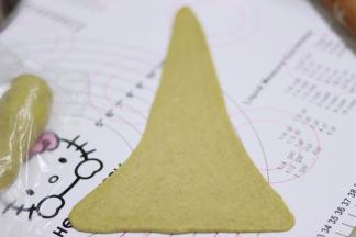 取第一个搓好的胡萝卜型的面团，用擀面杖，擀开成长长的三角形，尽量做到等边。三角形的底边最后可以轻轻的捏出尖角。这步如果擀开的时候，面团不好擀还回缩，就是没有静置好，需要继续静置。