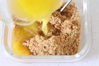 饼干碎末放入容器，倒入融化的黄油，搅拌均匀使得饼干充分的和黄油融合。