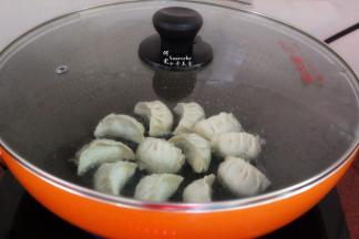 加一勺清水，盖上盖子，大火煮沸，转为中火，把饺子煮熟，并把水煮干，揭开盖子。