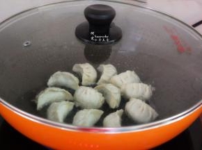 加一勺清水，盖上盖子，大火煮沸，转为中火，把饺子煮熟，并把水煮干，揭开盖子。