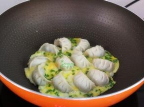 把调均鸡蛋倒入锅中，让蛋液和饺子完美融合，把鸡蛋煎熟，金灿灿即可上桌。