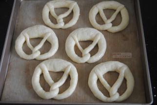 带着手套抓起面团放入碱水，两面浸泡各20秒左右，捞出沥干水分放入垫有油布或油纸的烤盘里。