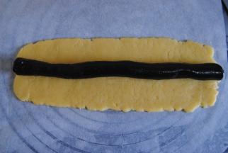 将面团和芝麻馅分成3份，芝麻馅搓成长条，面团擀成芝麻馅一样的长度，将面皮包裹起芝麻馅。