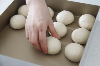 静置好的面团再次收圆，排入方形烤盘中。