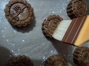 取出月饼，放置手温，用毛刷沾上一点点蛋液，用毛尖的五分之一处，轻轻并且快速的在月饼表面刷几下。