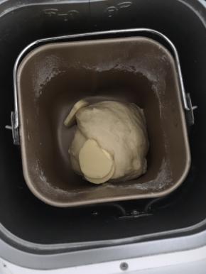 将除黄油以外的材料放入面包机桶内，启动和面程序揉10分钟之后加入黄油，继续揉面