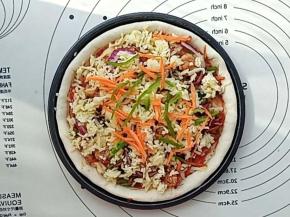 再把之前炒好的馅料铺在上面，摆上洋葱圈。然后再铺一层马苏里拉芝士，最后把之前留的青椒丝和胡萝卜丝撒在上面。