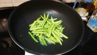 锅里热油放入一半蒜爆香，倒入四季豆放少许盐调味