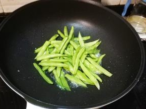 锅里热油放入一半蒜爆香，倒入四季豆放少许盐调味