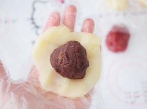 取一份原味的面团，按压成圆形，放入豆沙馅
