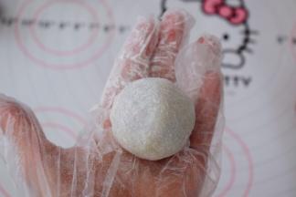 利用虎口慢慢往上推，收紧收口，再揉成光滑的圆球状，表面撒上熟粉