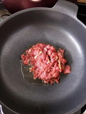 把锅烧热，倒入适量花生油。然后倒入牛肉，大火快速翻炒。