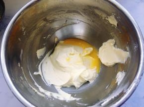 然后分次加入打散的全蛋液，继续用电动打蛋器充分打匀，每加入一次蛋液打匀后再加入下一次蛋液，直到蛋液和黄油充分融合。