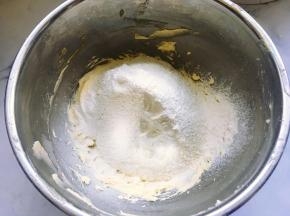 将低筋粉和泡打粉混合均匀后过筛，加入到打发的黄油蛋液中。
