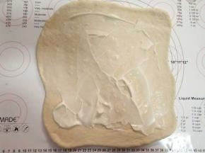 将面团擀成方形大片，翻面，涂上沙拉酱。