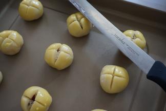 收口朝下，摆放在烤盘上，在表面刷上蛋黄液（蛋黄液干之后，可以再刷一遍）。用利刀划十字，切到能见到馅料