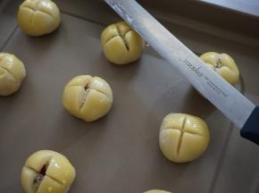 收口朝下，摆放在烤盘上，在表面刷上蛋黄液（蛋黄液干之后，可以再刷一遍）。用利刀划十字，切到能见到馅料