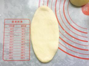 将松弛好的面团擀成椭圆形，用手拍掉两边的气泡。