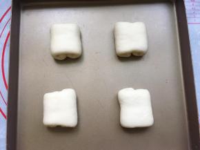 翻面后，日式牛奶面包胚就做好了，将面包胚整齐地码入烤盘里，并隔开一定的距离。这样做的目的是为了防止面包胚发酵烘烤后连在一起，影响美观。