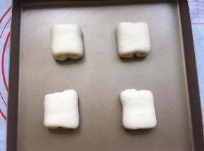 翻面后，日式牛奶面包胚就做好了，将面包胚整齐地码入烤盘里，并隔开一定的距离。这样做的目的是为了防止面包胚发酵烘烤后连在一起，影响美观。