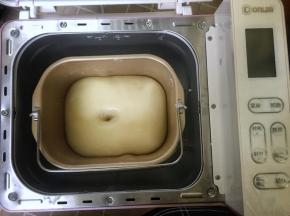 首先将除黄油以外的所有食材放入面包桶里，用筷子搅匀至没有干粉的状态，然后启动面包机开始揉面，揉至面团粗膜状态时加入软化的黄油，继续揉至完全扩展阶段，即面团光滑而有光泽，面团撑开是有韧性的薄膜状态，盖上面包机盖子，让面团在室温26度的环境下发酵至两倍大。