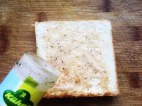 开始制作三明治，首先在吐司表面抹上法式沙拉酱，抹均匀。