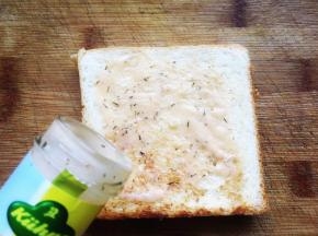 开始制作三明治，首先在吐司表面抹上法式沙拉酱，抹均匀。