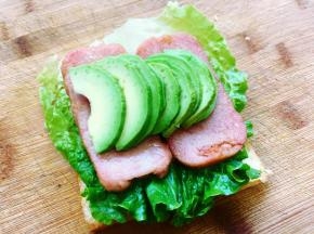 接着在午餐肉上码上牛油果，牛油果是一片挨着一片叠放的，在牛油果上撒上少许海盐和黑胡椒碎调味。