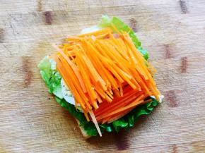 在牛油果的上面铺上三片鸡蛋，再铺上胡萝卜丝，两侧比较空的位置也铺上胡萝卜丝，能铺多满就铺多满。