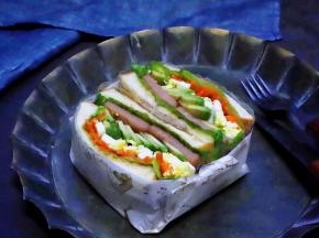 切成两半的三明治并排放在一起，然后用油纸叠成一个小纸盒，将三明治放在纸盒里，牛油果鸡蛋午餐肉三明治就做好了。