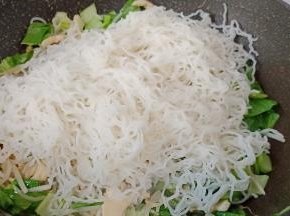 下泡好的米线，用2双筷子不停地翻炒出水份。