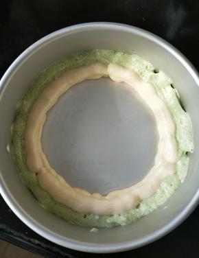 先在模具里挤一圈绿色蛋糕糊，接着挤一圈原味的，然后再重复一遍这个动作。(如图所示)