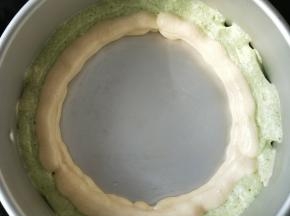 先在模具里挤一圈绿色蛋糕糊，接着挤一圈原味的，然后再重复一遍这个动作。(如图所示)