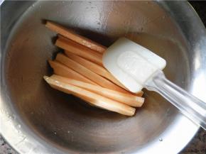 准备一个干净碗，将切好的薯条放入碗中，倒入玉米油和蜂蜜，用硅胶刮刀进行翻拌，将薯条混合均匀。