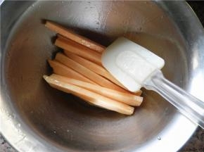 准备一个干净碗，将切好的薯条放入碗中，倒入玉米油和蜂蜜，用硅胶刮刀进行翻拌，将薯条混合均匀。