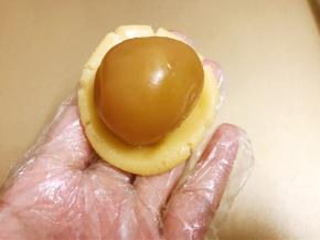 取一份饼皮压扁包入一颗蛋黄莲蓉