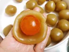取一份莲蓉拍扁包入一整颗咸蛋黄